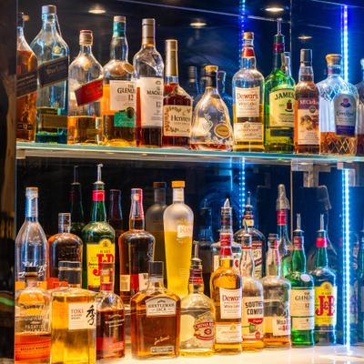 Collection of liquor bottles on a backlit bar shelf.