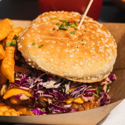 Fish Burger topped with cheese and red cabbage, served with crinkle-cut fries.
