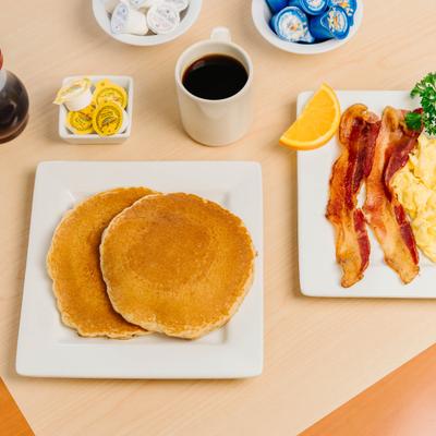 Pancake breakfast with bacon, scrambled eggs, and coffee.