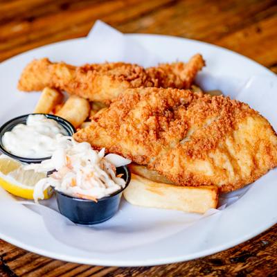 Fish and chips with tartar sauce, coleslaw, and a lemon slice on the side.