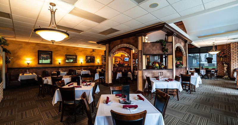 Interior seating area with chairs and tables set with white tablecloths