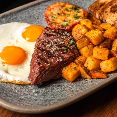 Steak and eggs served with home fries and toasted bread.