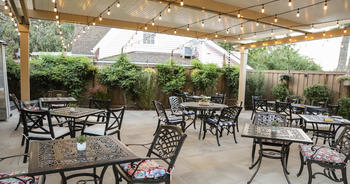 Exterior, covered seating area, tables and chairs under large pergola, lanterns