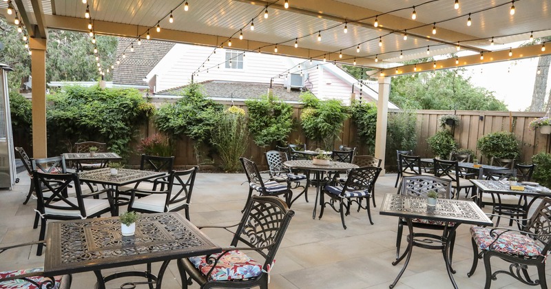 Exterior, covered seating area, tables and chairs under large pergola, lanterns