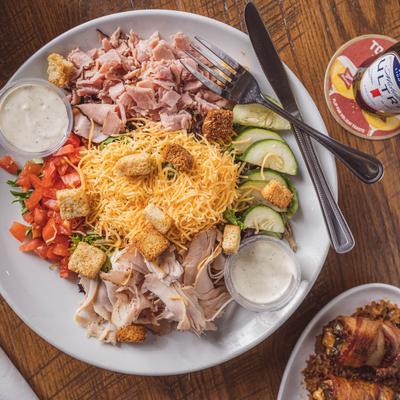 Chef salad accompanied by dipping sauces and a beer