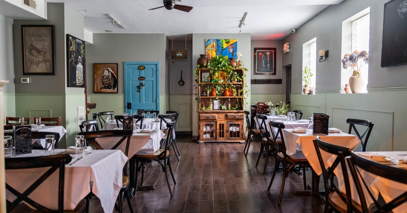Interior with white-tablecloth dining tables, black chairs and colorful wall art