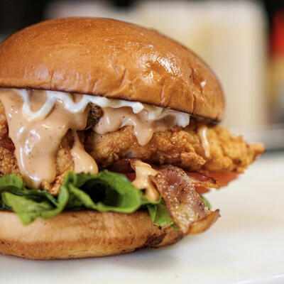 Burger with fried chicken, bacon, and lettuce.