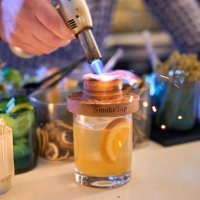 Bartender torching a smoked citrus cocktail.