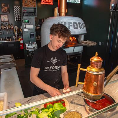 Pizza chef preparing food behind a counter.