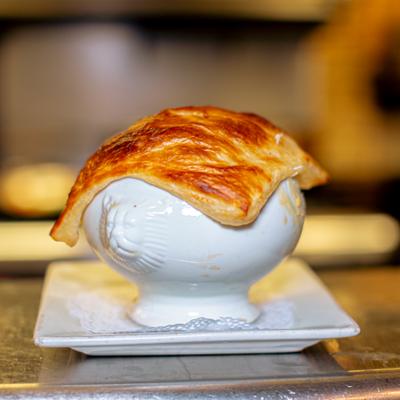 Puff pastry on top of a white soup bowl.