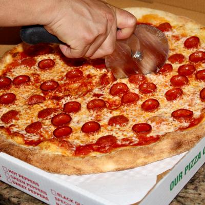 Pizza being cut with a pizza cutter.