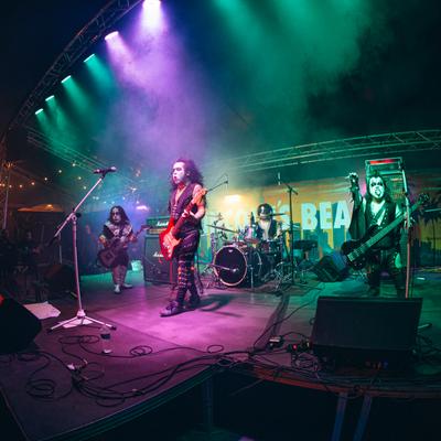 Rock band performing on the stage beneath a colorful lights.