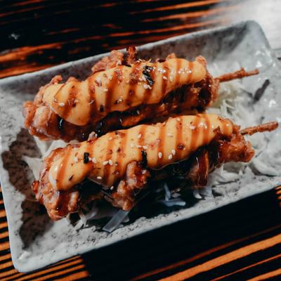 Two Karaage chicken skewers served on a textured plate.