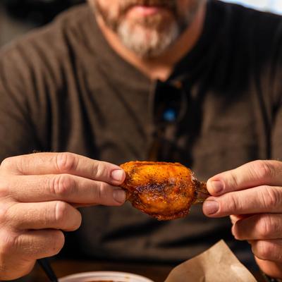 A person holding a chicken wing
