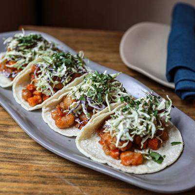 A plate of tacos with beer-battered sweet potato morsels and coleslaw.