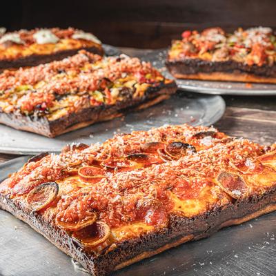 Pepperoni pizza with assorted pizzas in the background.