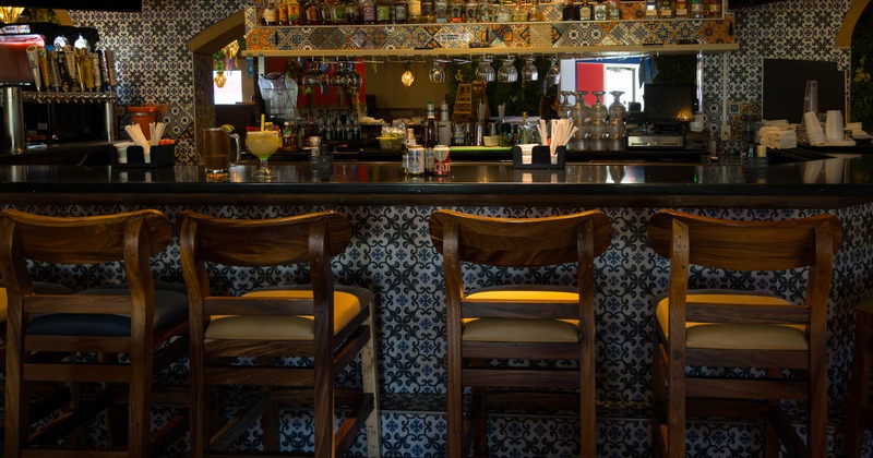 Restaurant bar with patterned tiles, wooden stools, and liquor shelves