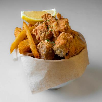 Fried salmon bites with fries and a lemon wedge.