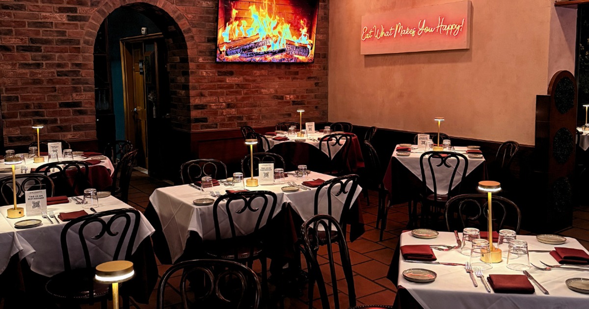 Dining area featuring elegantly set tables, neon sign, and fireplace screen on a wall