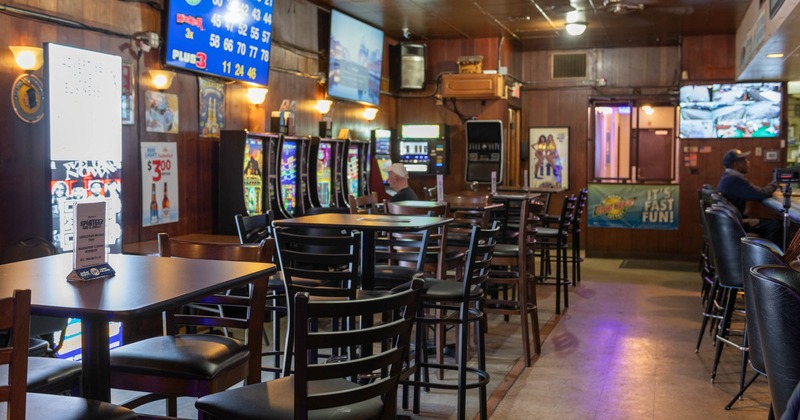 Inside, wooden tables with chairs, slot machines and TVs