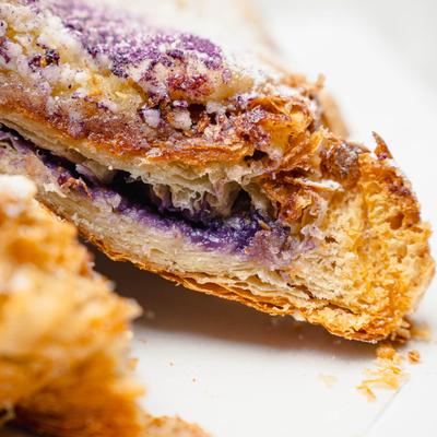 Cross-section of a flaky pastry with purple filling and powdered sugar.