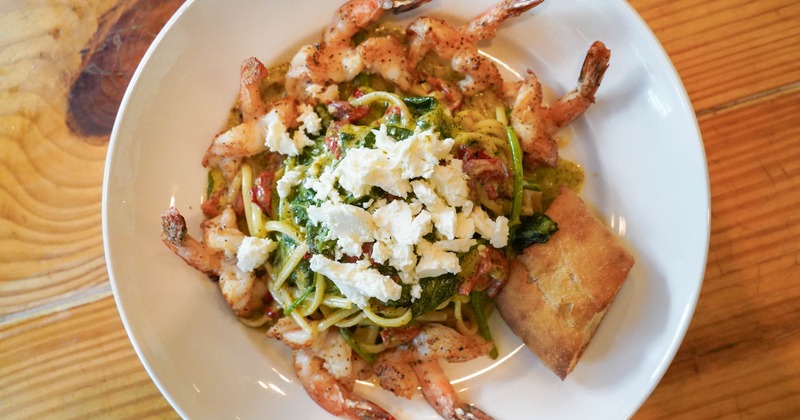 Shrimp pasta topped with crumbled cheese and greens