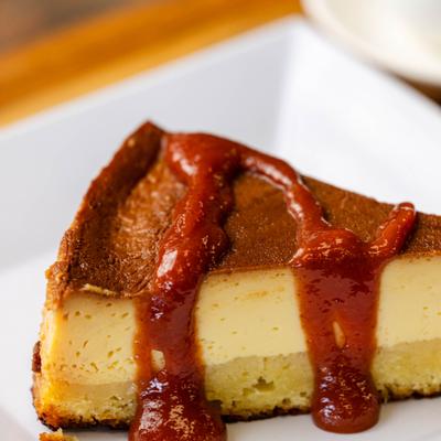 Guava flan cheesecake with a thick fruit coulis topping, close up.