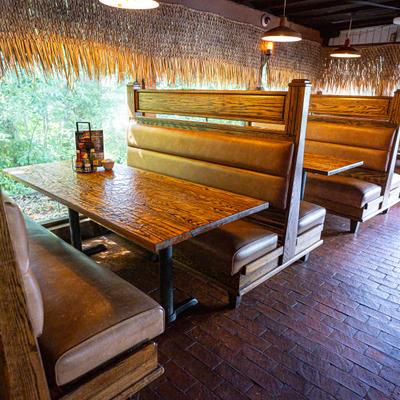 Rustic restaurant booths featuring wood tables, leather seating, and thatch.