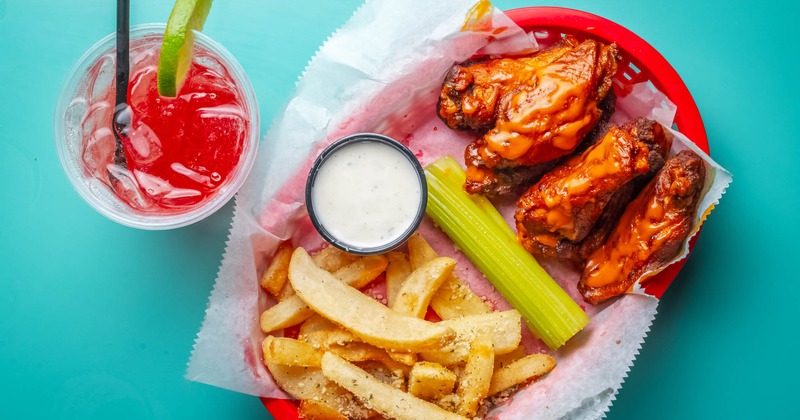 Chicken wings, fries, celery, ranch dressing, and a cocktail