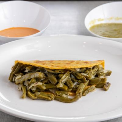Folded tortilla filled with grilled cactus strips on a white plate.