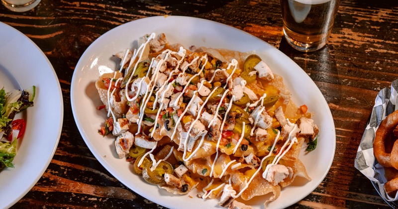 Loaded nachos topped with chicken pieces and a drizzle of sauce