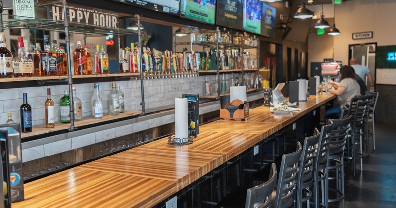 A loon wooden bar top with draft beer taps and spirit bottles displayed on shelves