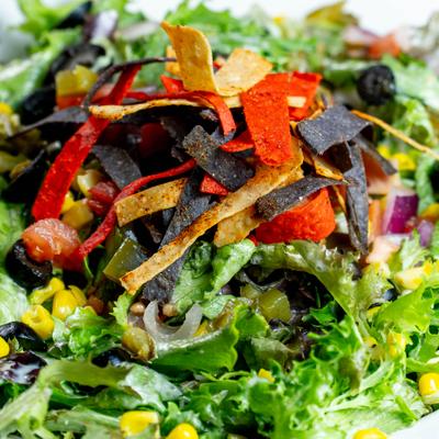 Salad topped with corn, jalapenos, lives, pico de gallo, tortilla chips and cheese.