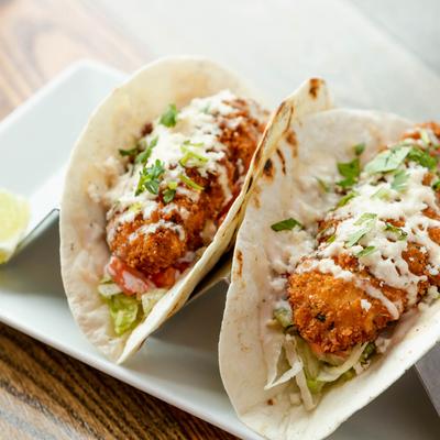 Crispy chicken tacos, with lettuce, cilantro, cheese, tomato, and spicy lime aioli.
