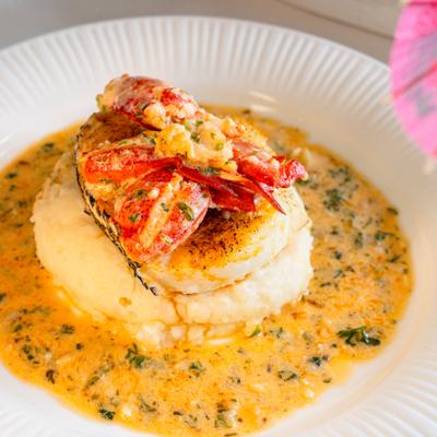 Grilled fish with lobster and mashed potatoes in creamy sauce with herbs.