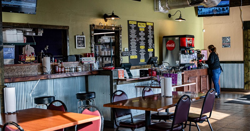 Interior, seating area, checkout counter, large menu board, soda fountain on the left