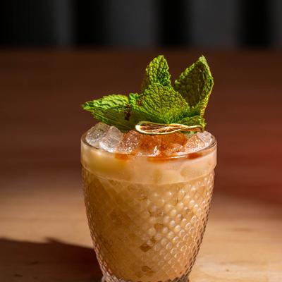Mai Tai in a textured glass, garnished with mint leaves and dry citrus wheel.