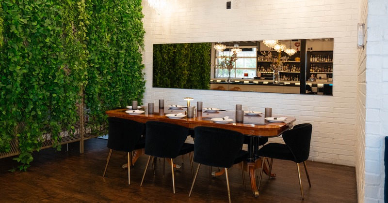 Dining area with a wooden table, black chairs, living green wall