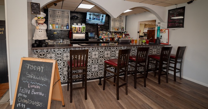 Restaurant bar area with patterned counter, bar stools and a sandwich board with daily specials