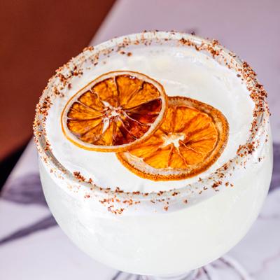 Chili-rimmed coconut margarita, garnished with dried orange wheels.