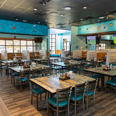 Wide dining area with tables and chairs,  booth seating and large windows.