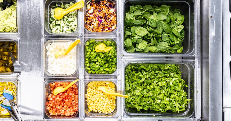 Salad bar with various fresh ingredients in plastic containers