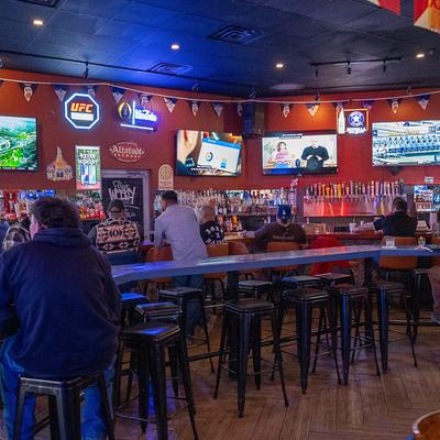 Interior, bar, bartender, tv screens, bar table in front, bar stools, guests.