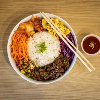 White rice, beef, carrots, corn, kimchi, egg, purple cabbage, and Korean chili sauce.