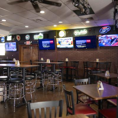 Interior with high-top seating, neon signs, and TVs.