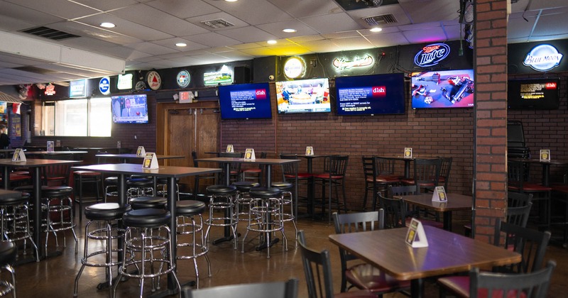 Interior, tables with stools and wall TV sets