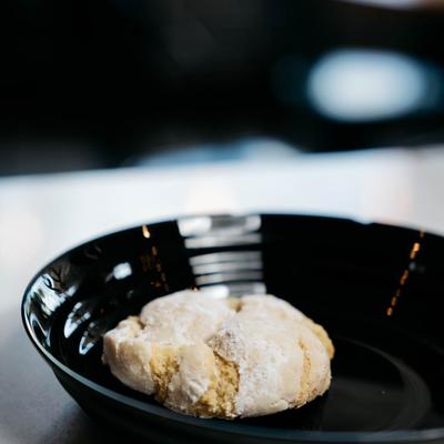 A cream cheese lemon crinkle cookie on a black plate.
