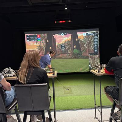 Guests enjoying a game of indoor golf simulator inside Up an Downs Golf Bar.