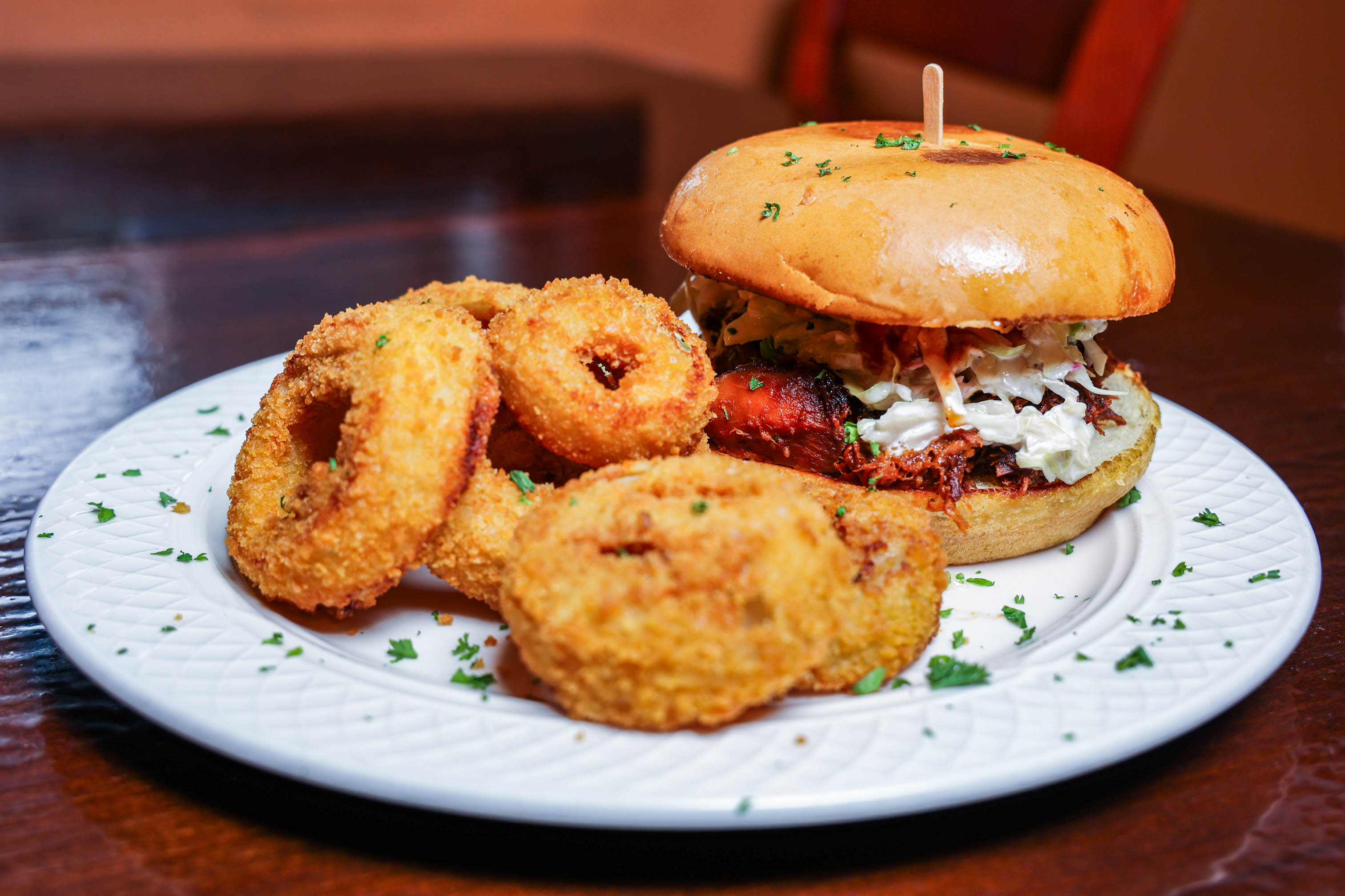 Pulled pork sandwich served with fried onion rings