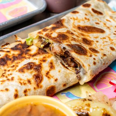 A plate of quesadillas stuffed with meat and melted cheese,  served with sides.